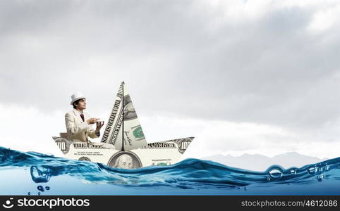 Businessman in boat made of dollar banknote. Successful businessman sailing on dollar boat in financial sea