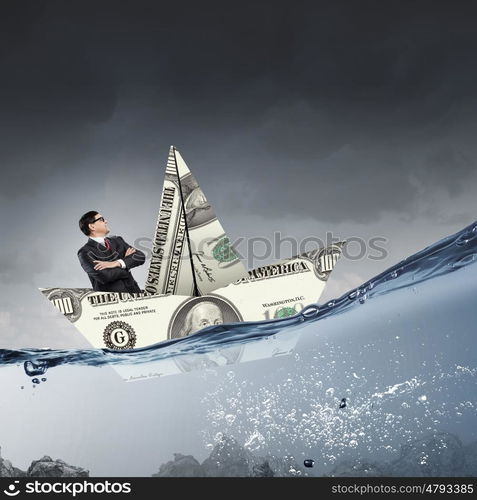 Businessman in boat made of dollar banknote. Successful businessman sailing on dollar boat in financial sea