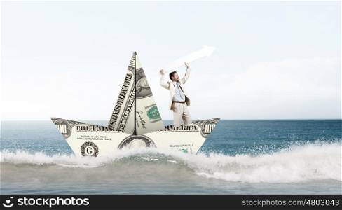 Businessman in boat made of dollar banknote. Successful businessman sailing on dollar boat in financial sea