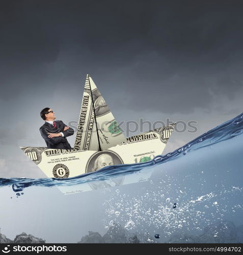 Businessman in boat made of dollar banknote. Successful businessman sailing on dollar boat in financial sea