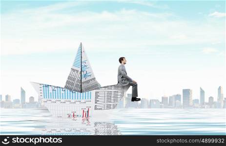 Businessman in boat made of paper. Successful businessman sailing on paper boat in financial sea