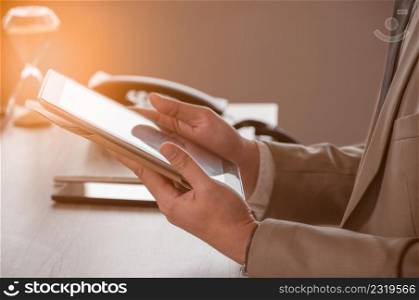 Businessman in brown suit working with digital tablet PC while sitting at office desk. Business application and digital technology concept