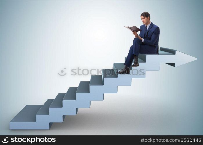 Businessman in career ladder concept reading book