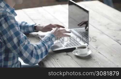 Businessman in casual clothes using laptop in office, his collegue giving document