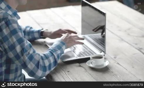 Businessman in casual clothes using laptop in office, his collegue giving document