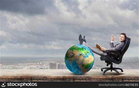 Businessman in chair. Young businessman sitting in chair with book in hands. Elements of this image are furnished by NASA