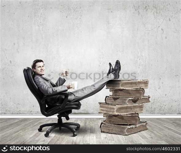 Businessman in chair. Young businessman sitting in chair with cup in hands
