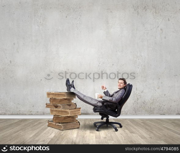 Businessman in chair. Young businessman sitting in chair with cup in hands