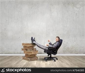 Businessman in chair. Young businessman sitting in chair with cup in hands