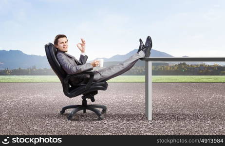 Businessman in chair. Young businessman sitting in chair with cup in hands