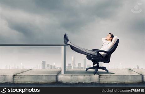 Businessman in chair. Young businessman sitting relaxed in chair with legs on table