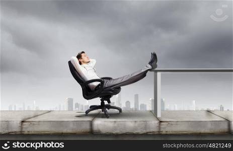Businessman in chair. Young businessman sitting relaxed in chair with legs on table