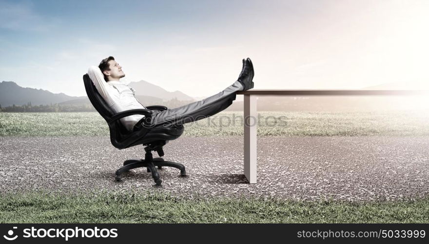 Businessman in chair. Young businessman sitting relaxed in chair with legs on table