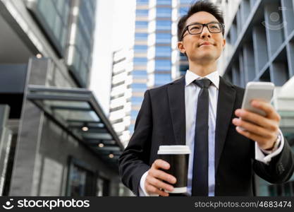 Businessman in city holding his mobile. I am always in touch with ny company