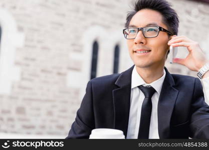 Businessman in city holding his mobile. I am always in touch with ny company