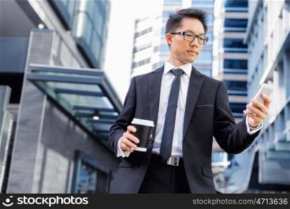 Businessman in city walking and holding his mobile. Technology is a part of my life