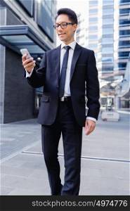 Businessman in city walking and holding his mobile. Technology is a part of my life