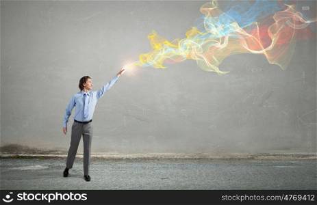 Businessman in concrete room. Businessman reaching hand to touch colorful fumes above head