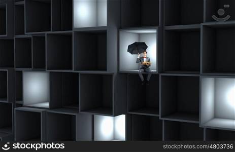 Businessman in cube. Miniature of businessman with umbrella sitting in cube