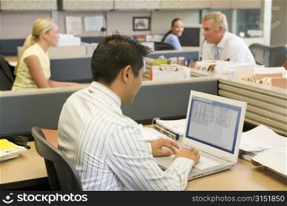 Businessman in cubicle at laptop