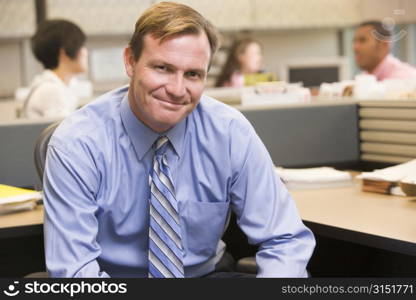 Businessman in cubicle smiling