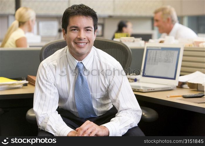 Businessman in cubicle smiling