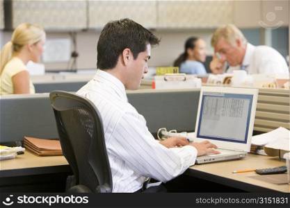 Businessman in cubicle using laptop