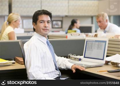 Businessman in cubicle with laptop