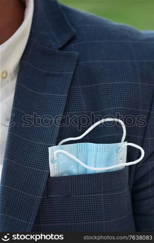 Businessman in elegant clothes, with a medical mask sticks out of a pocket