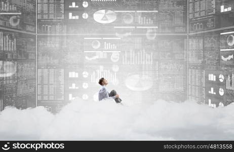 Businessman in empty room. Young businessman sitting on cloud in room and infographs on wall