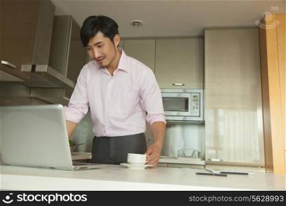 Businessman in front of his computer drinking coffee at home