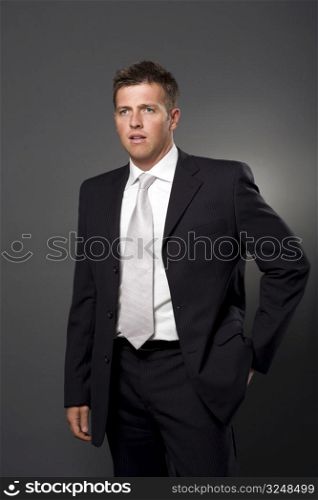 Businessman in full-suit standing with hand in pocket.