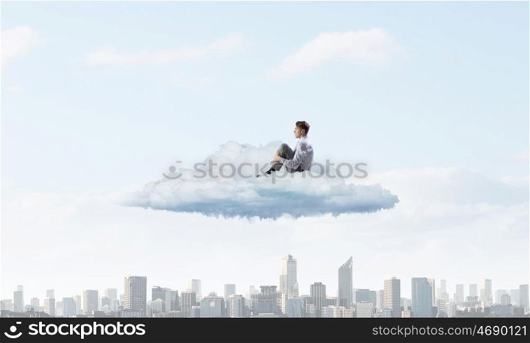 Businessman in isolation. Depressed young businessman sitting alone on cloud high in sky