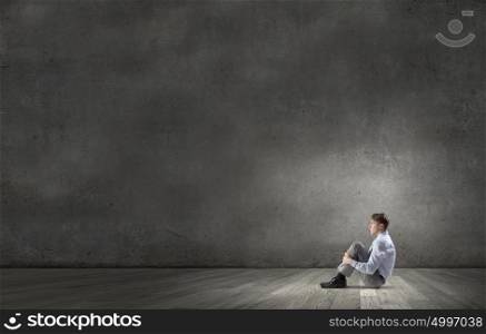 Businessman in isolation. Young depressed businessman sitting on floor alone in empty room