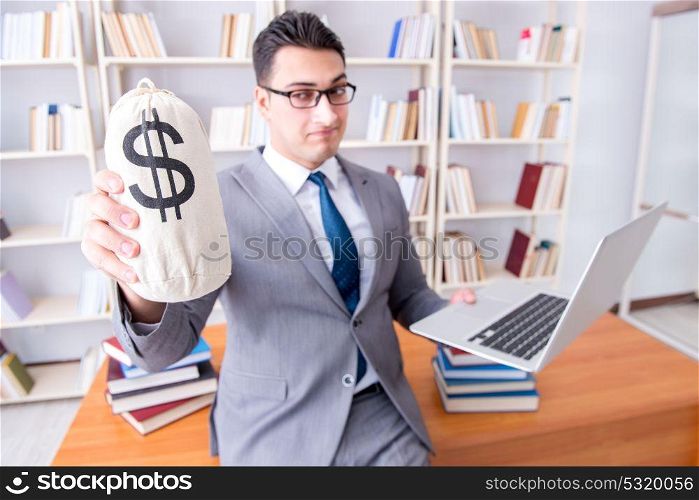 Businessman in library with a money sack and a laptop