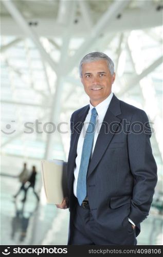 Businessman in Lobby of Modern Building carryiong file folder with out of focus people in background
