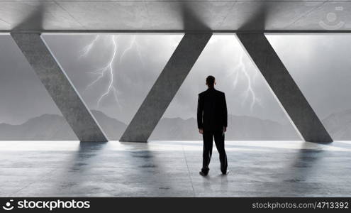 Businessman in modern interior. Back view of businessman in modern room looking in office window