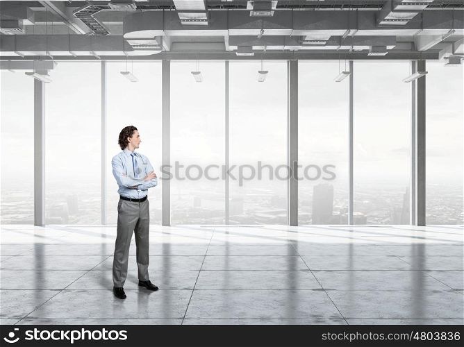 Businessman in modern interior. Confident businessman standing with arms crossed on chest in modern office