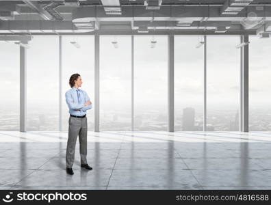 Businessman in modern interior. Confident businessman standing with arms crossed on chest in modern office