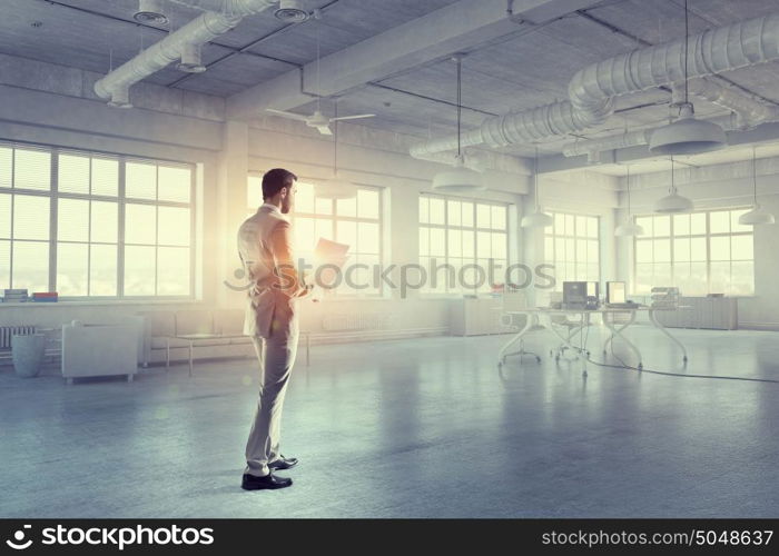 Businessman in modern interior mixed media. Busy businessman making notes and writing something in his organizer at his office