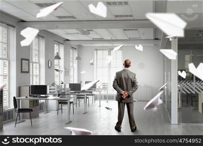 Businessman in office interior. Thoughtful businessman standing with back in empty office