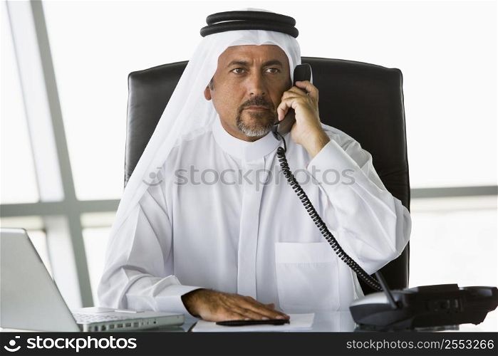 Businessman in office on telephone by laptop (high key/selective focus)