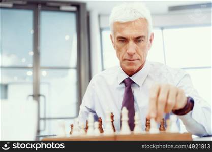 Businessman in office playing chess. Thinking the next move