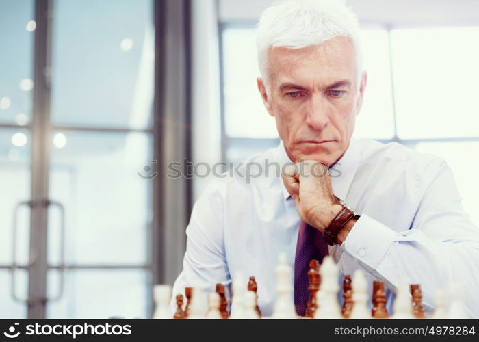 Businessman in office playing chess. Thinking the next move