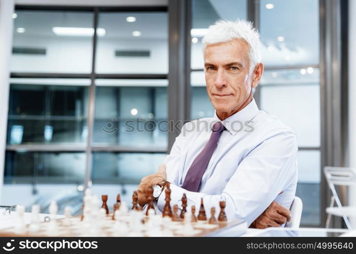 Businessman in office playing chess. Thinking the next move