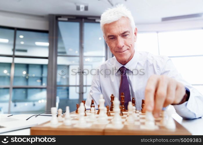 Businessman in office playing chess. Thinking the next move