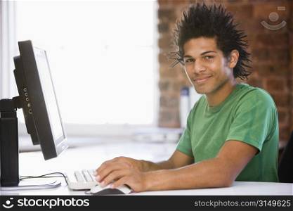 Businessman in office using computer and smiling