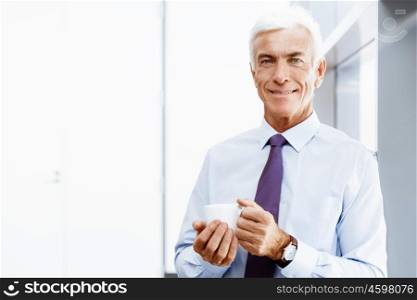 Businessman in office with a cup. Time for coffee