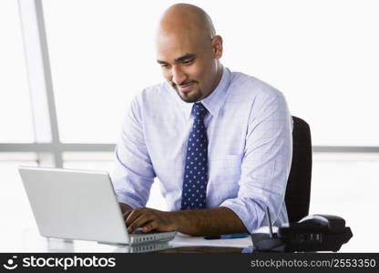 Businessman in office with laptop smiling (high key/selective focus)