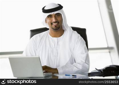 Businessman in office with laptop smiling (high key/selective focus)